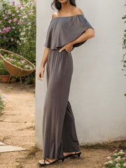 Off-the-shoulder flounce jumpsuit in dark gray with wide-leg pants.