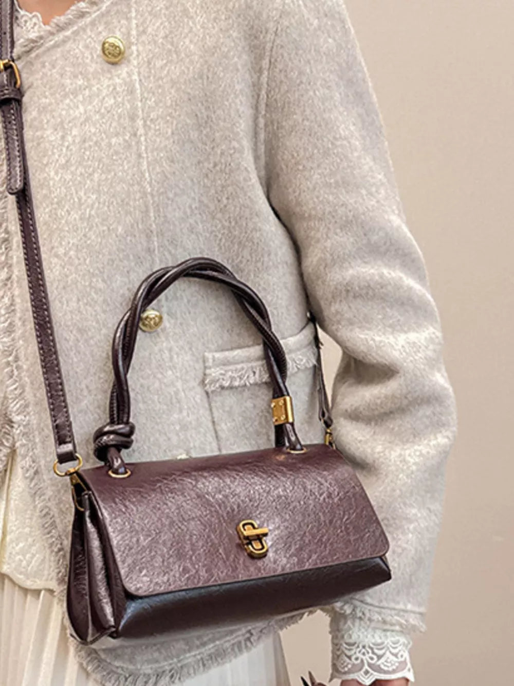 Chic crossbody bag in brown with twisted handle and gold clasp.