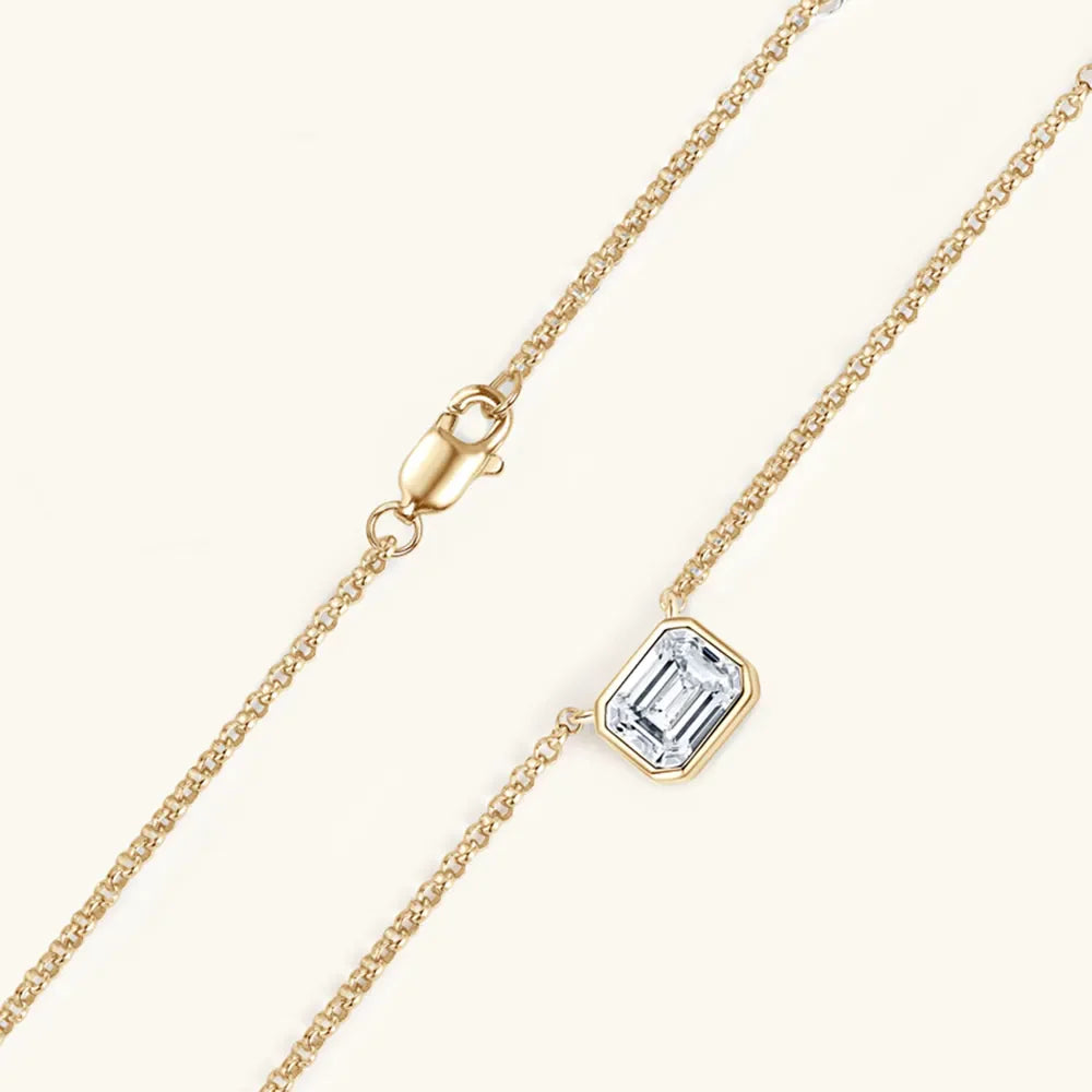 Gold necklace with emerald cut moissanite in bezel setting and lobster clasp.