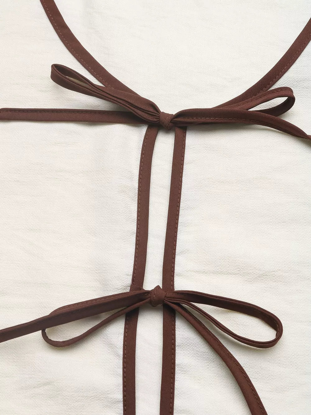 Chic tie-front two-piece ensemble in beige with brown trim and bow details.