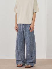 Men's distressed wide-leg acid wash denim jeans in blue with ripped details.