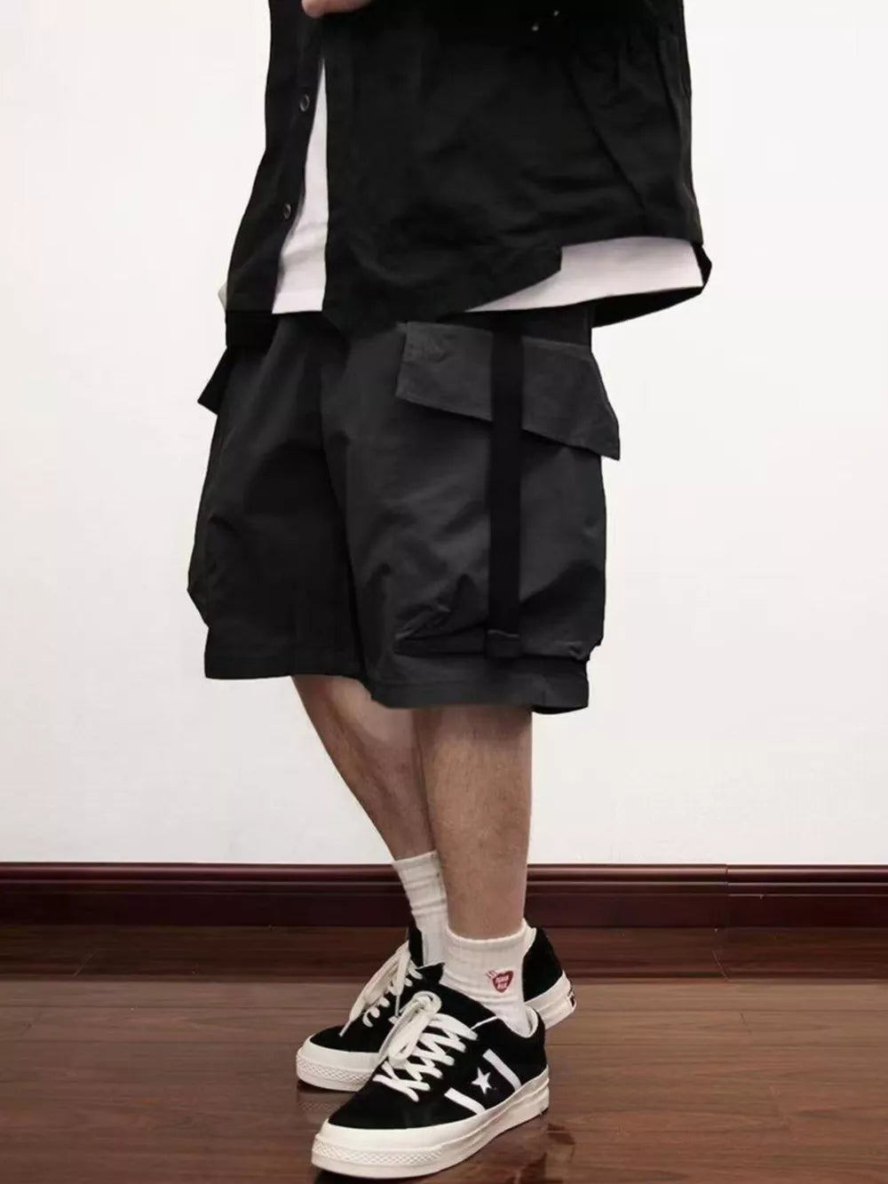 Black relaxed fit cargo shorts with large flap pockets and strap detail.