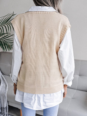 Cream openwork cable knit vest with ribbed hem, layered over a white collared shirt.