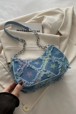 Denim shoulder bag with starburst pattern and frayed edges, blue strap and chain detail