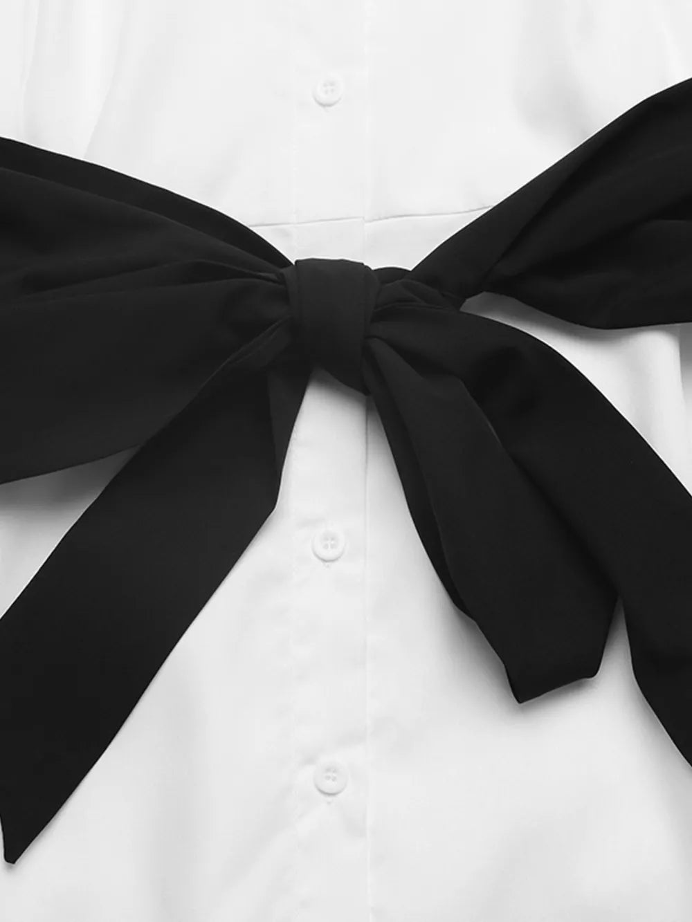 White midi shirt dress with black bow tie detail and button front.