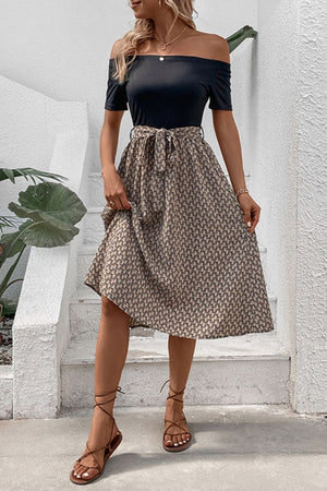 Black off-shoulder midi dress with a patterned A-line skirt and tie waist