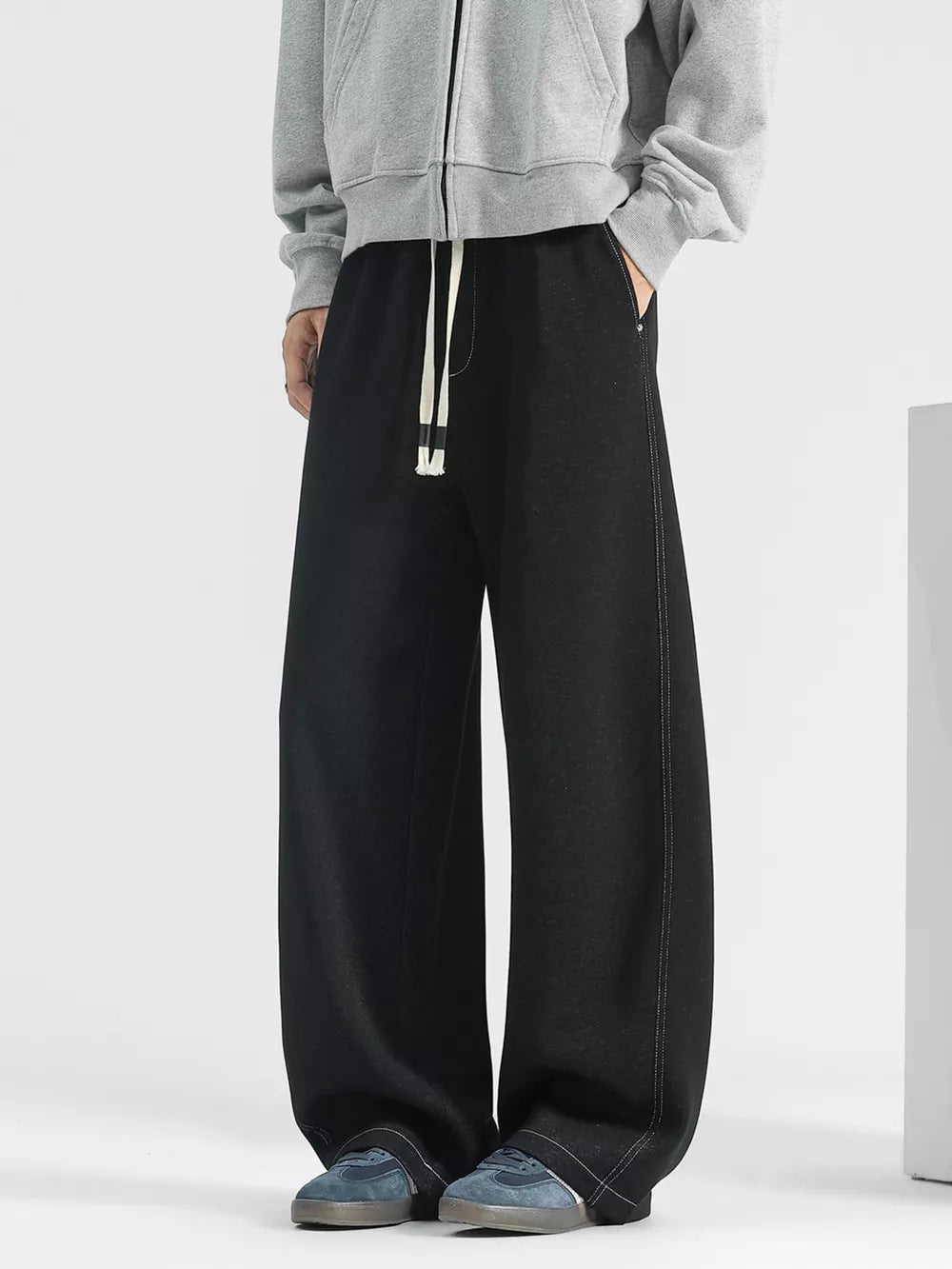Men's black loose fit drawstring jeans with wide leg and contrast stitching detail.