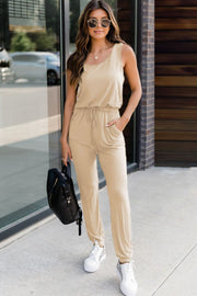 Tan relaxed drawstring waist jumpsuit with scoop neck and pockets.