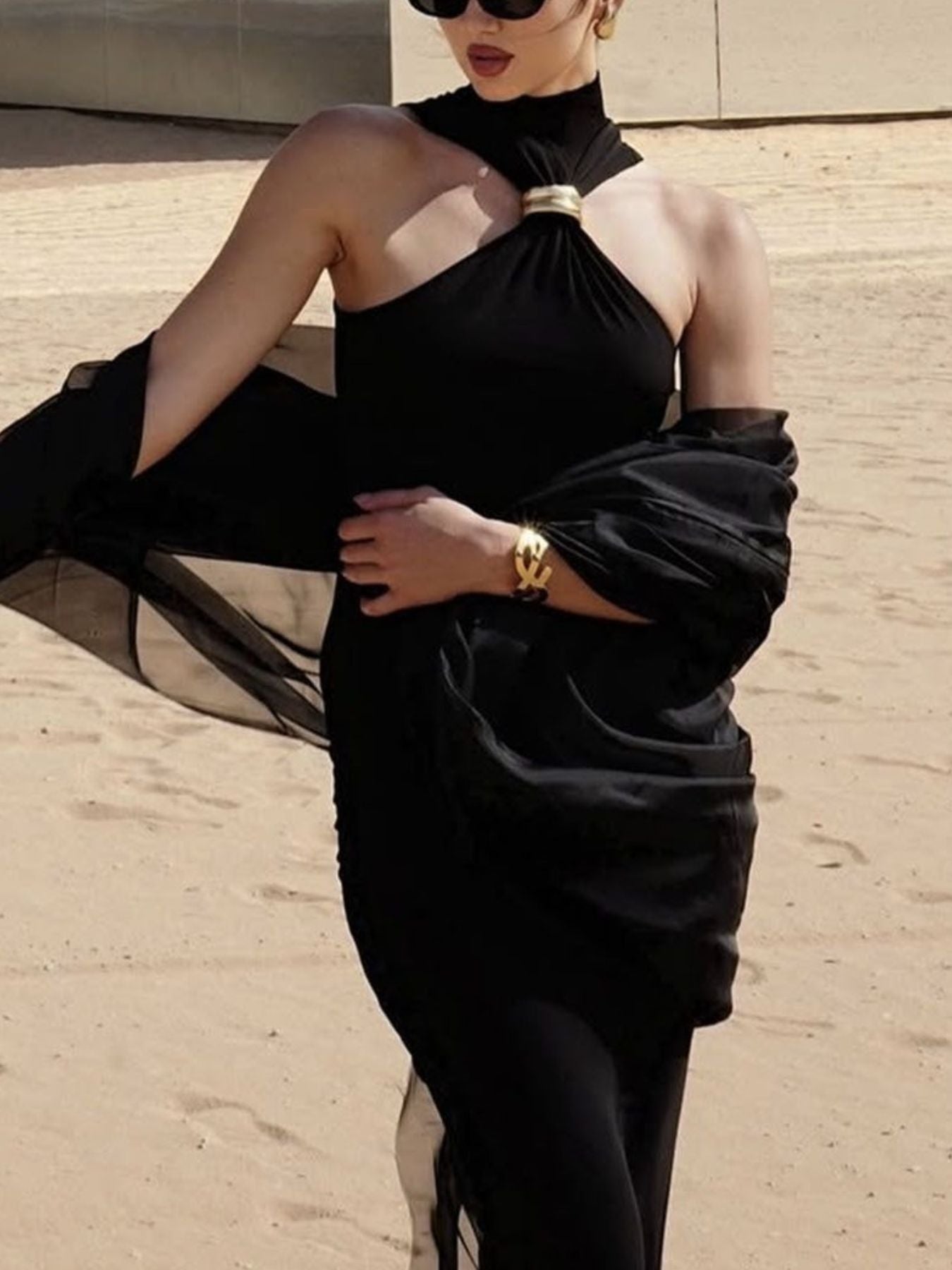 Black asymmetrical halter neck tank top with gold ring detail and sheer draped sleeves.