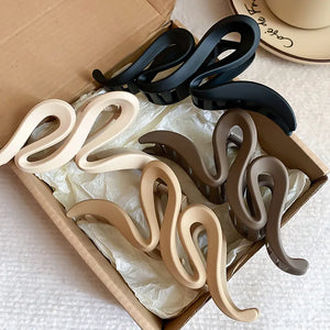 Sculptural hair claws in black, dust storm, coffee brown, and tan with serpentine design.