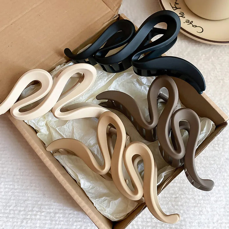 Sculptural hair claws in black, dust storm, coffee brown, and tan with serpentine design.