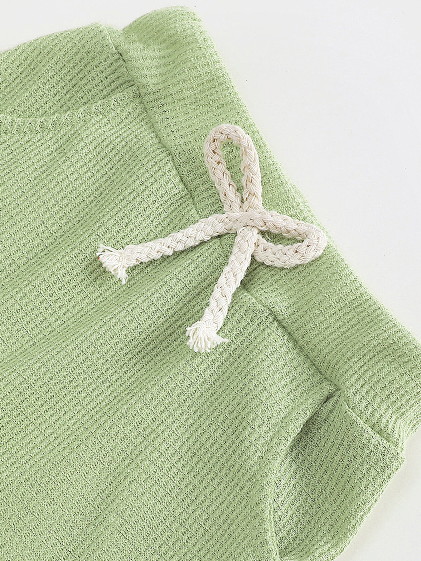 Green waffle knit children's pants with a decorative white drawstring bow.