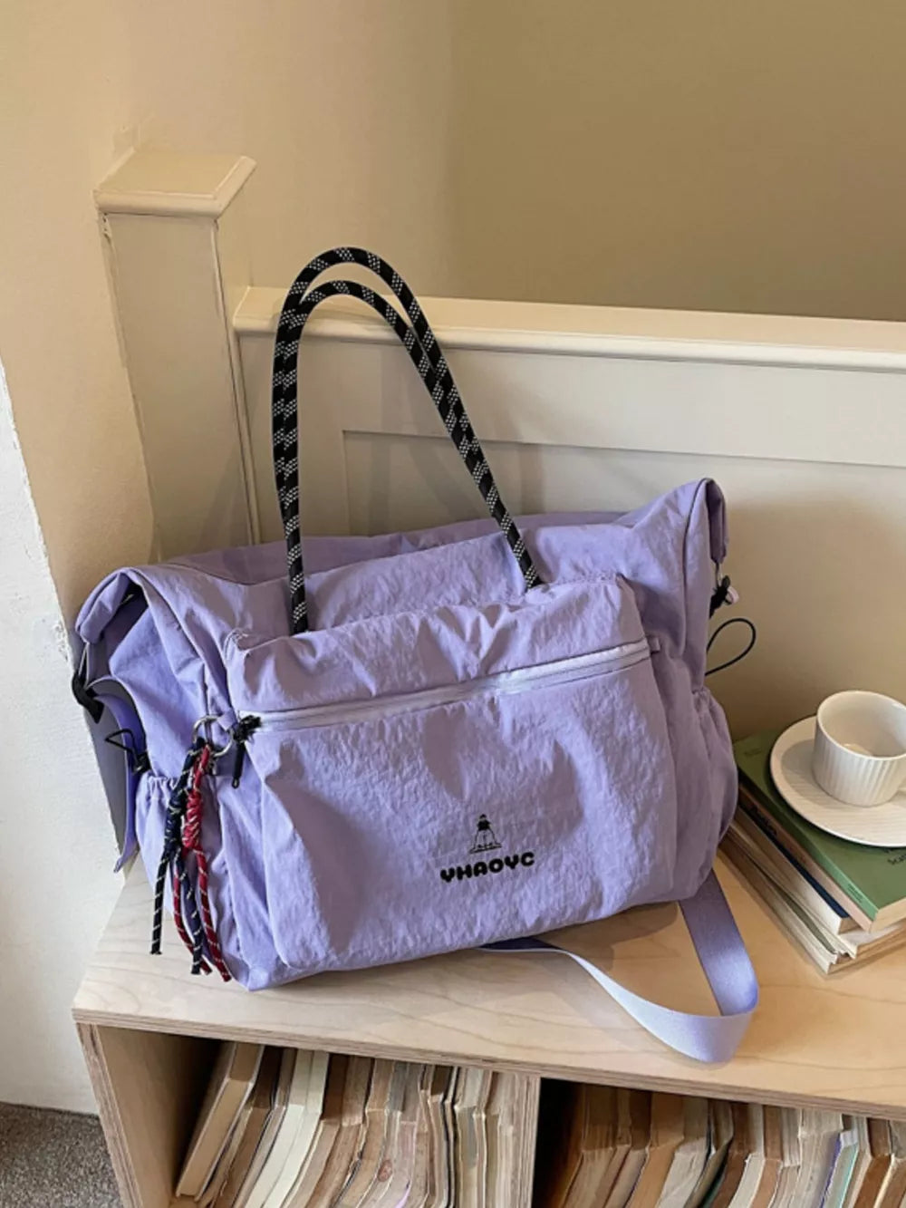 Chic Oxford cloth travel duffel bag in lavender with black and white rope handles and tassel details.