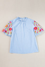 Light blue gingham blouse with embroidered floral sleeves and ruffled neckline.