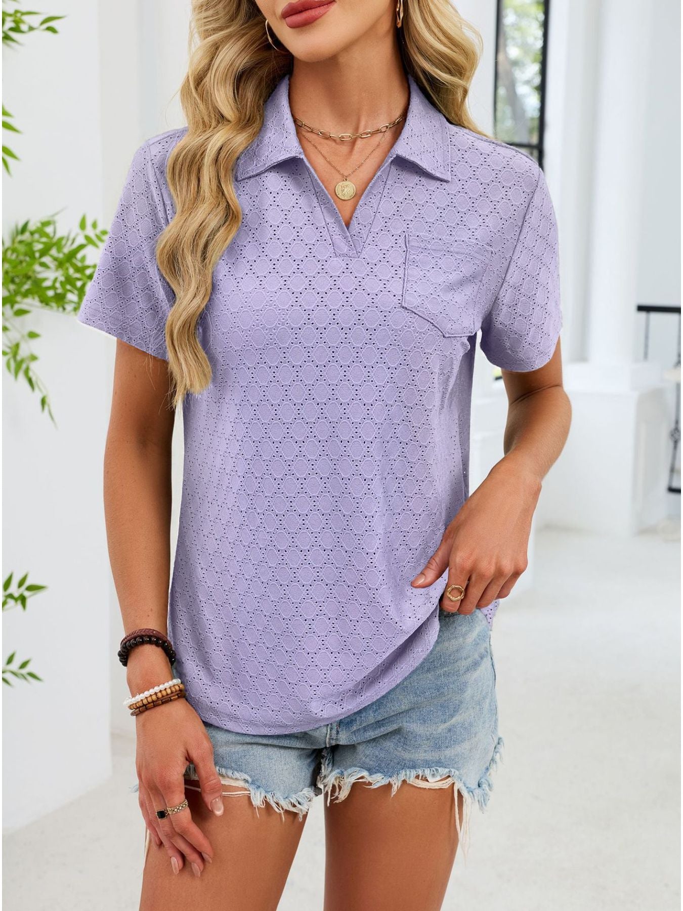 Lavender eyelet polo collar blouse with short sleeves and a chest pocket.