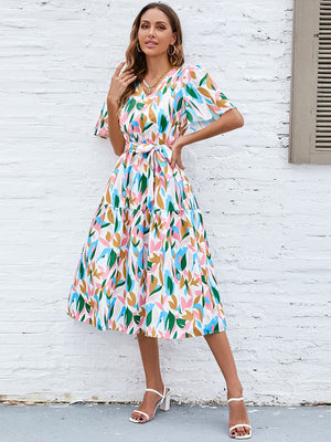 Botanical print midi dress with tie waist, flutter sleeves, and tiered skirt.