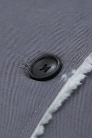 Sherpa-lined canvas button-down jacket in dark gray, showing a black button and fuzzy trim detail.
