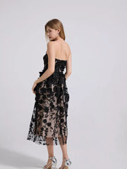 Black strapless midi dress with intricate floral applique and sheer overlay.