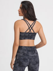 Crisscross back sports bra in dark gray tie-dye pattern with strappy details.