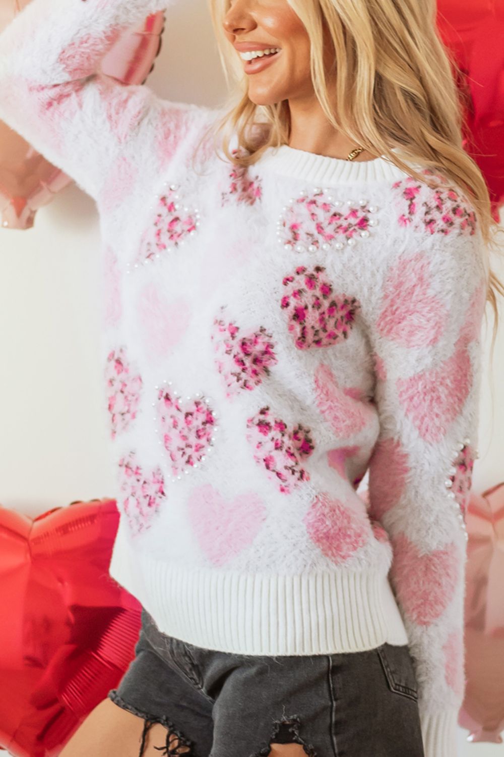 Fuzzy white knit sweater with pink heart jacquard pattern and pearl embellishments.
