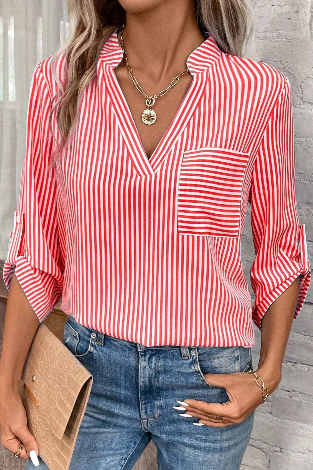 Red and white vertical stripe V-neck blouse with a chest pocket and roll-tab sleeves.