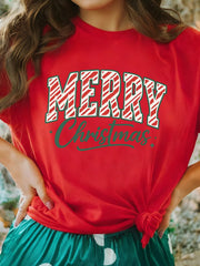 Red t-shirt with white and red striped Merry Christmas graphic and green script text.
