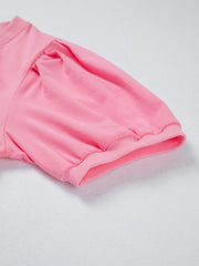 Pink cotton v-neck blouse with puffed short sleeves and ribbed cuffs.