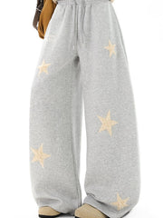 Gray wide leg sweatpants with drawstring and embroidered star appliques.