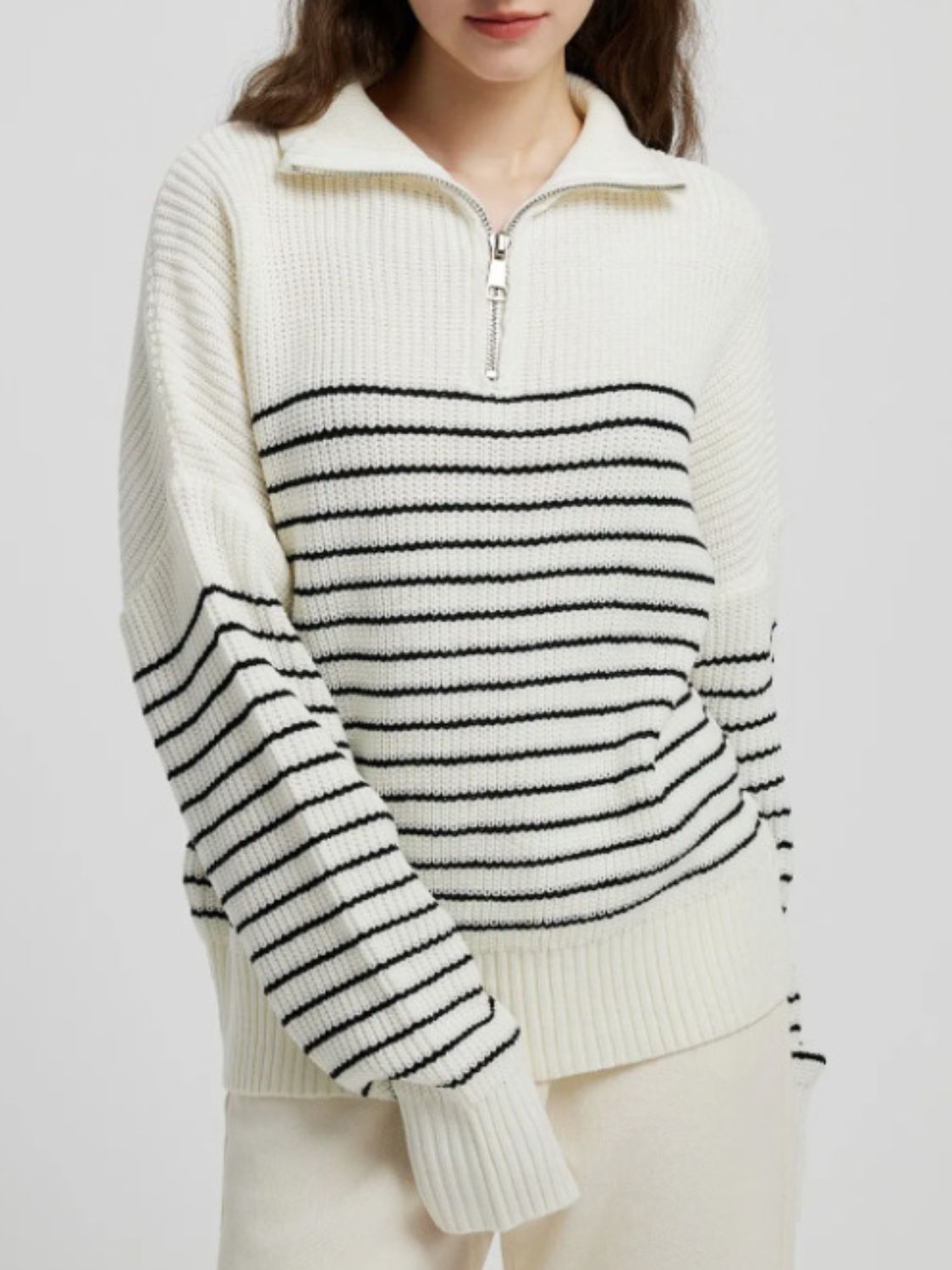 Cream ribbed knit sweater with black horizontal stripes and a half-zip neckline.