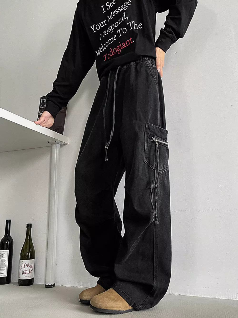 Black relaxed fit cargo jeans with drawstring waist and zippered pocket.