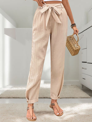 Tan textured linen paperbag trousers with tie waist and cuffed ankles.