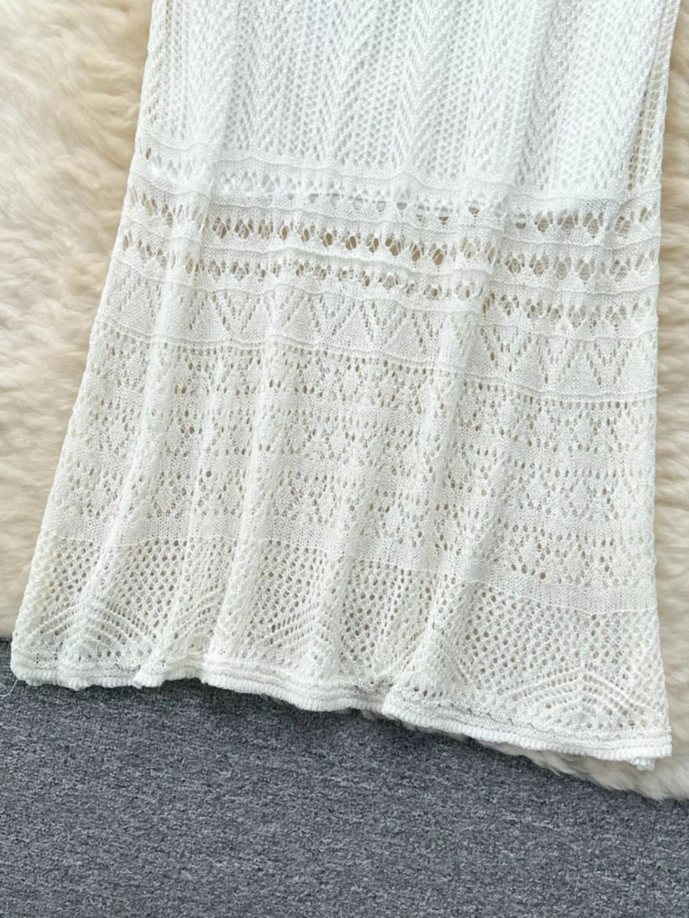 White openwork maxi skirt with intricate knit patterns and a flowing hem.