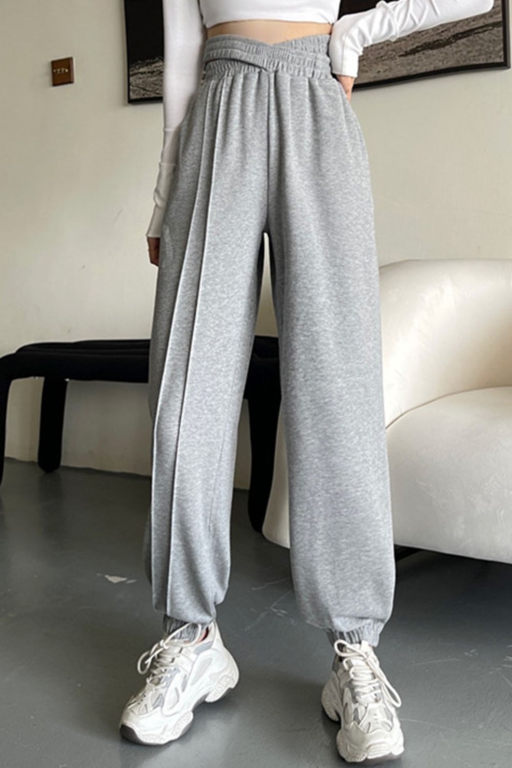 Gray Dawn joggers with pleated waistline and elastic cuffs, styled with sneakers.