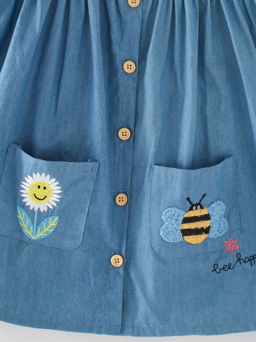 Denim dress with bee and flower embroidery, button front, and pockets.