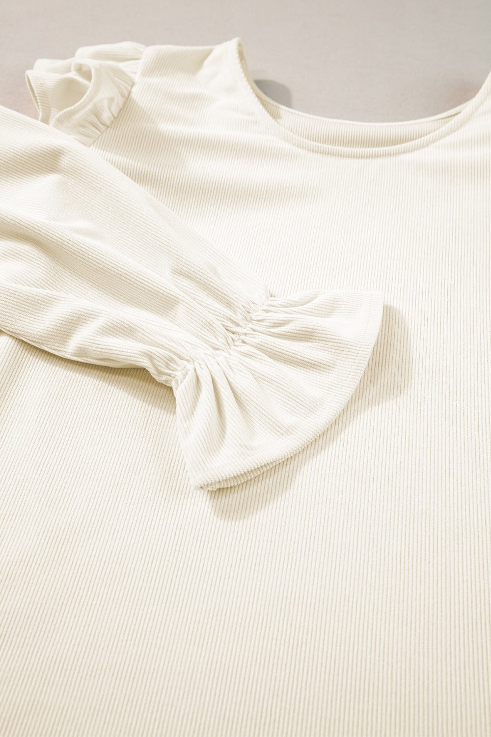 Textured ruffle sleeve blouse in eggshell with ribbed fabric and a scoop neckline.