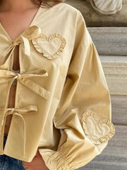 Pastel yellow blouse with heart appliqués and tie closures.