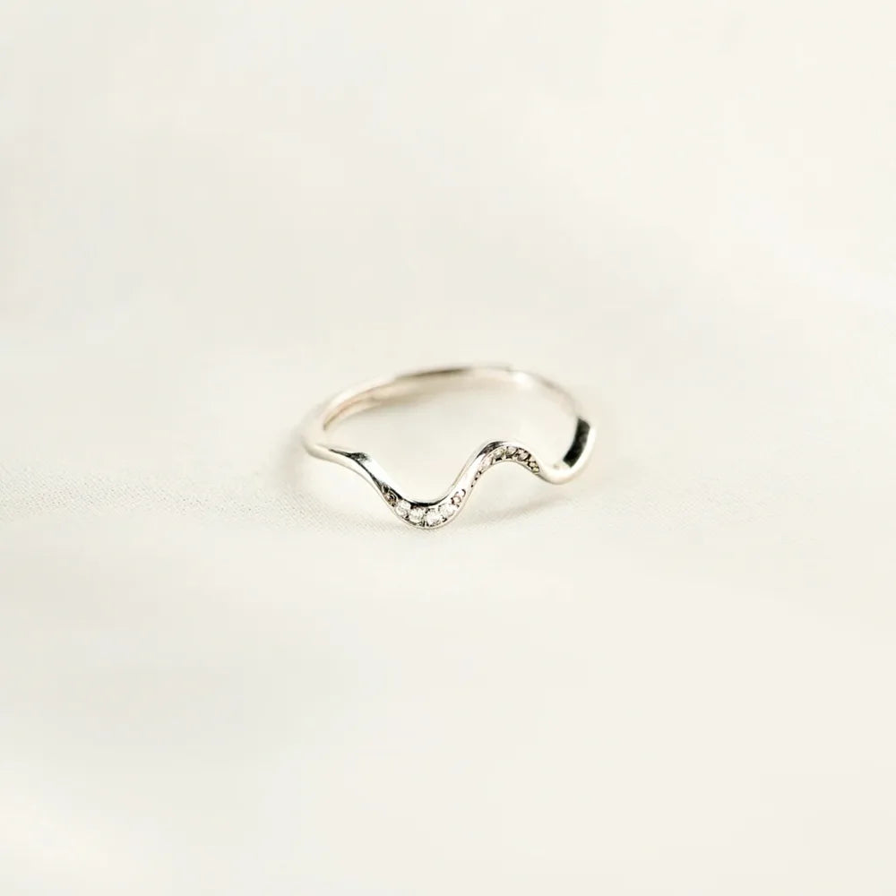Silver serpentine diamond contour ring with a wavy band.
