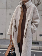 Oversized beige sherpa coat with brown suede accents and drawstring details.
