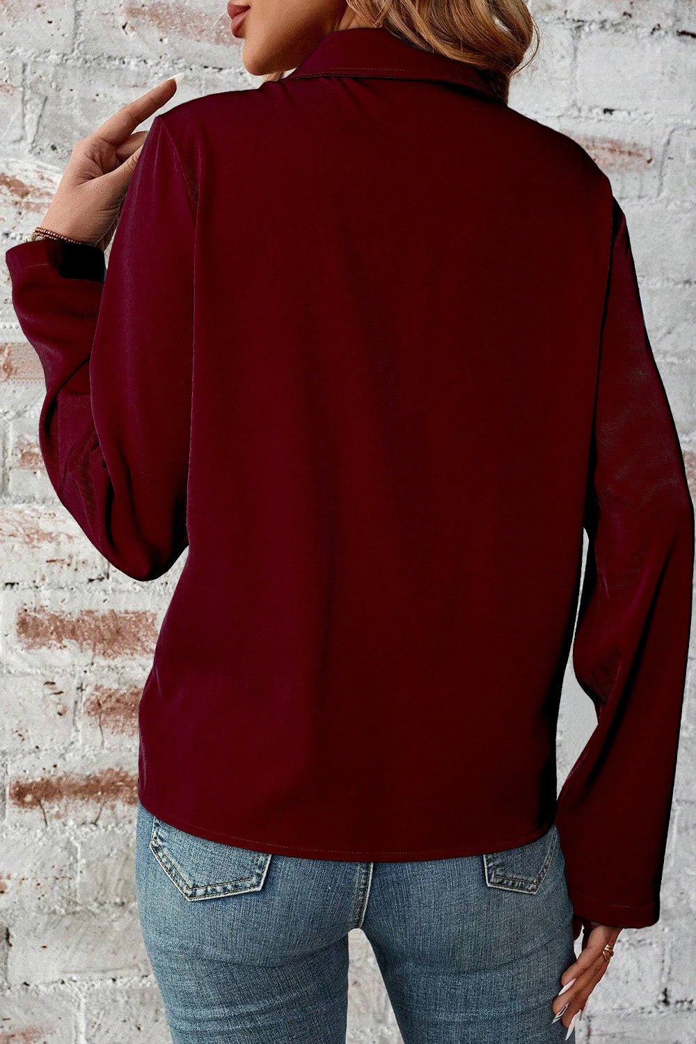 Burgundy zip-front blouse with long sleeves and collar, styled with jeans.