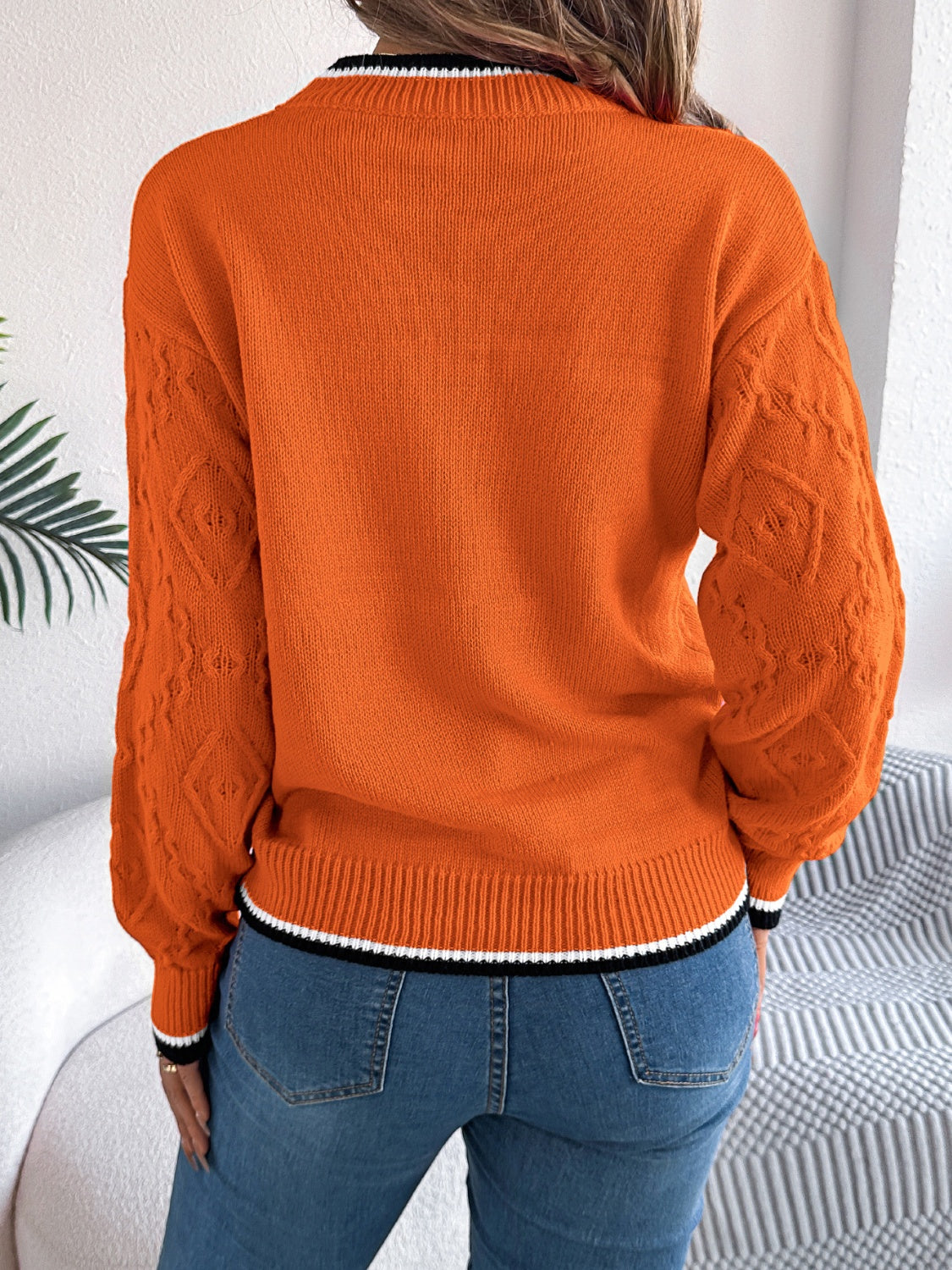 Orange knit sweater with diamond texture sleeves and contrast trim neckline and hem.