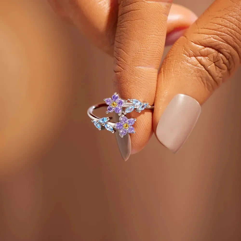 Silver ring with floral bypass design featuring purple and blue zirconia stones.