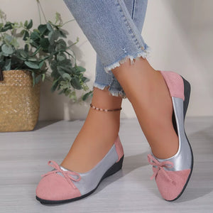 Pink and silver slip-on flats with bow detail and casual ankle jeans.