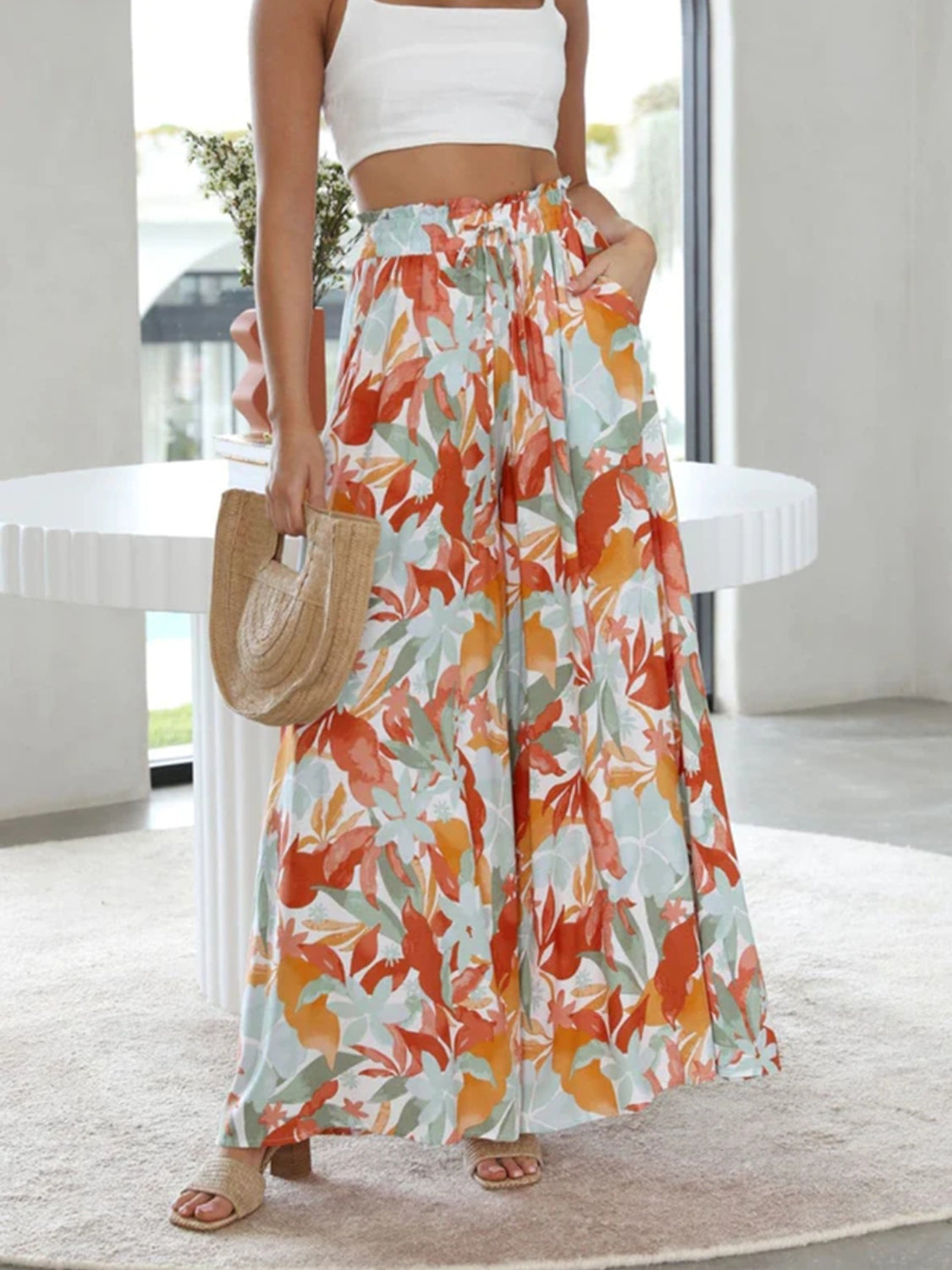 Pineapple print palazzo trousers in orange, turquoise, and sage with a drawstring waist and wide leg.