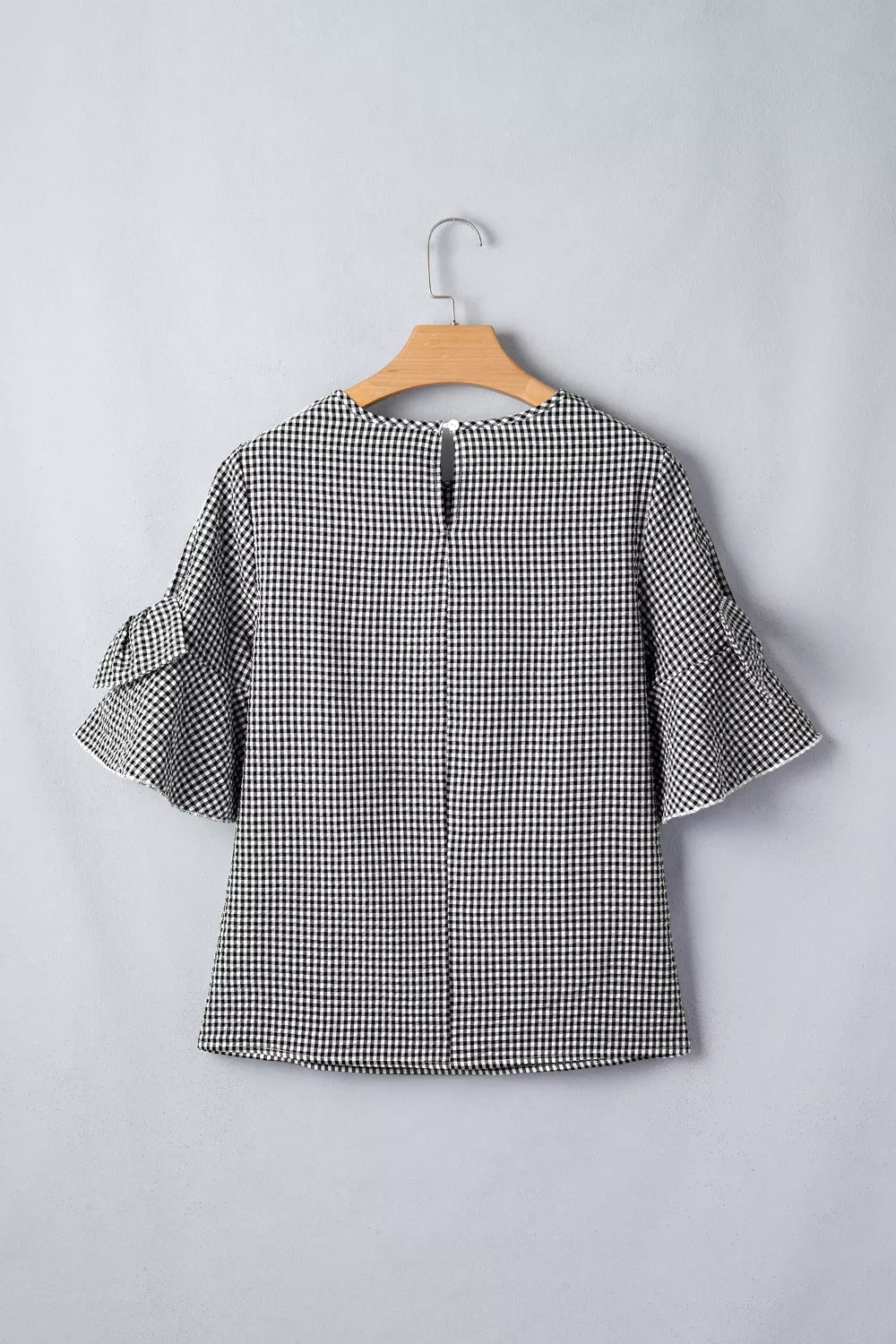 Black and white gingham polyester shirt with ruffled sleeves and a keyhole back detail.