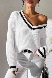 White ribbed knit sweater with V-neck, black trim, and pearl details on neckline and cuffs.