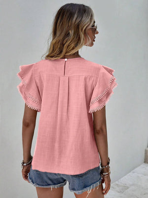 Dusty pink blouse with ruffle sleeves and pom-pom trim, featuring a keyhole back detail.