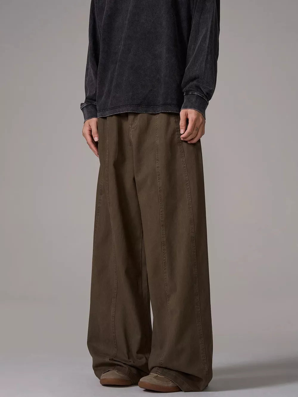 Brown wide-leg sweatpants with pockets and stitched seams, worn by a man.