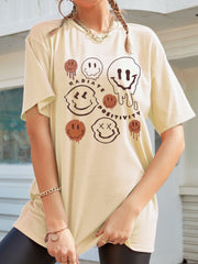 Tan oversized graphic tee with melting smiley faces and "Radiate Positivity" text.