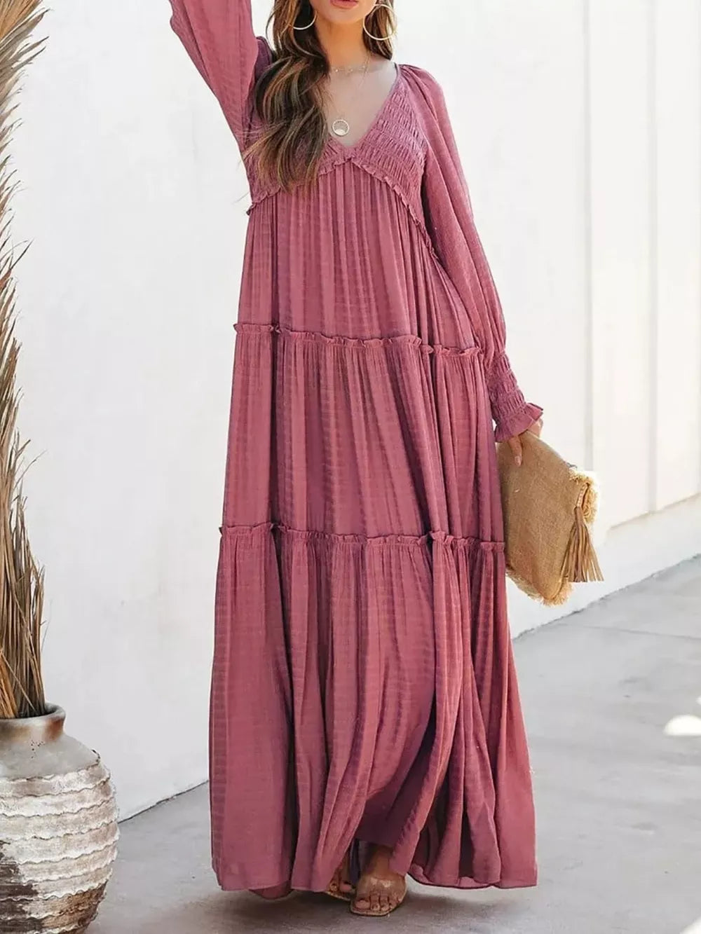 Smocked V-neck tiered maxi dress in wine red with long sleeves and a flowing skirt.