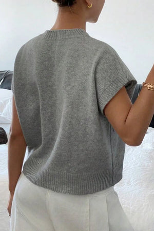Gray knit sleeveless top with ribbed neckline and hem, styled with white pants.